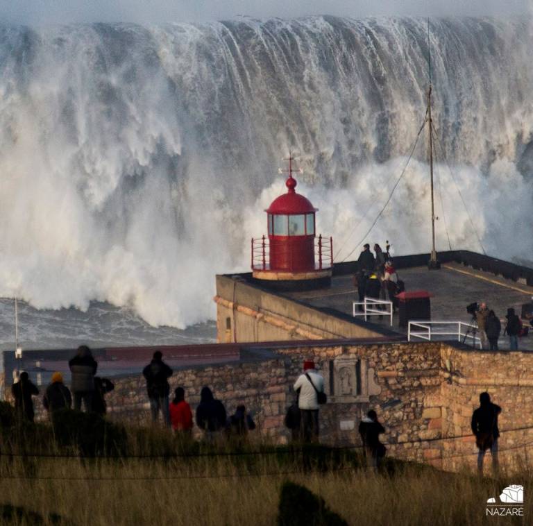 Image result for People gather to watch enormous waves at Praia do Norte in Nazare, Portugal"